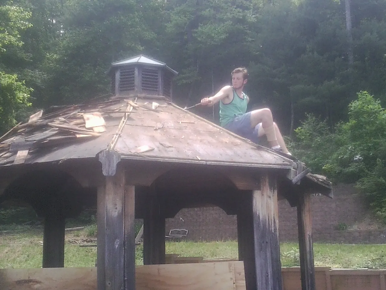 Tearing the old roof off a wooden gazebo before new shakes in Madisonville