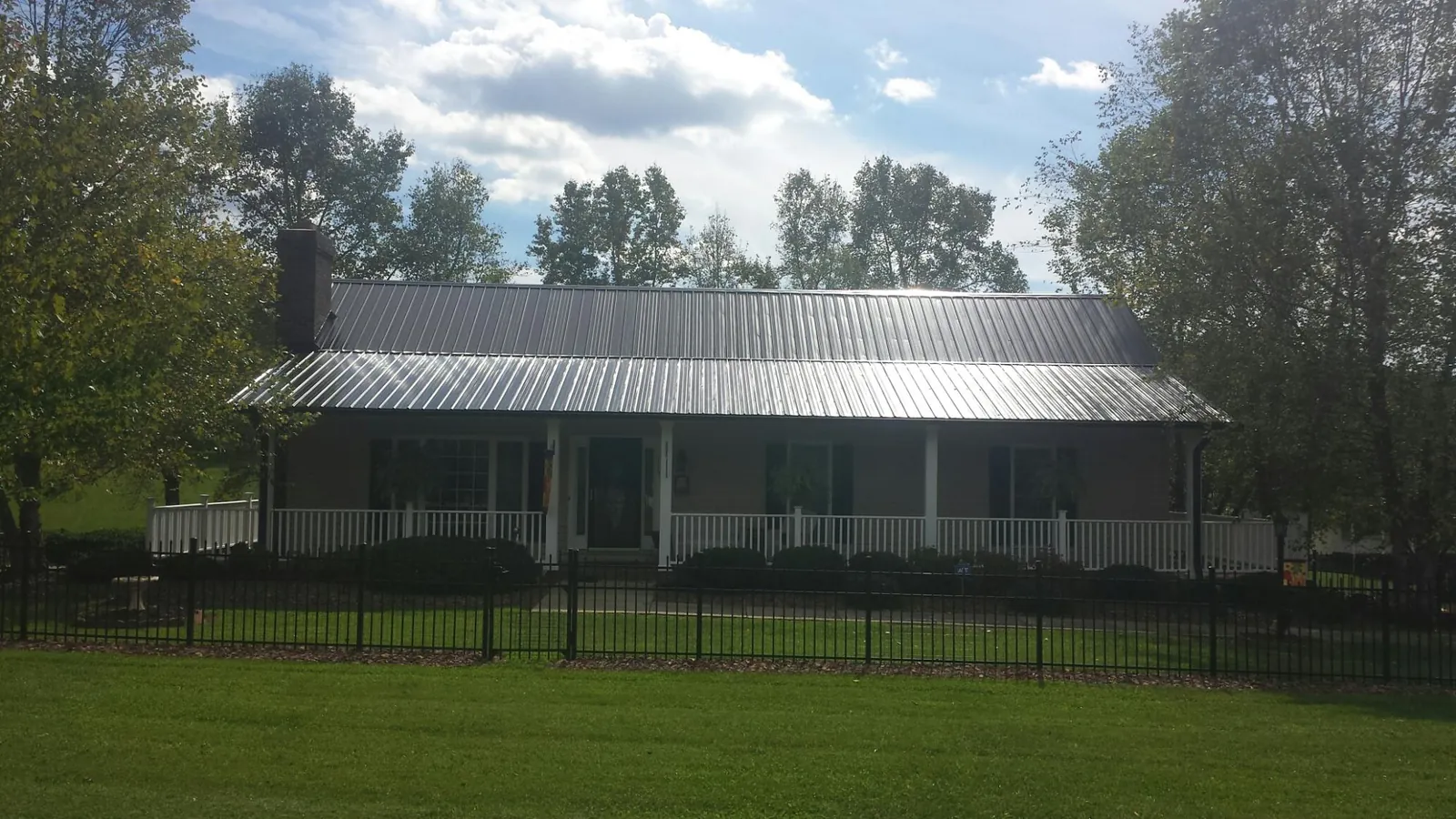 Gray metal roof on a brick ranch with a full width front porch — Gutter Guard Installation work by our crew in Madisonville